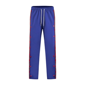 Detail of blue joggers featuring red and green plaid side stripes with red snap buttons