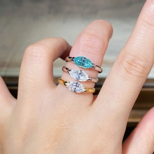 Close-up of three 925 silver marquise-cut rings in mint blue and white on a finger