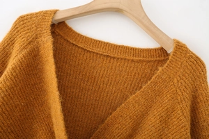 Close-up of mustard knit sweater neckline showing ribbed texture and shoulder seam detail