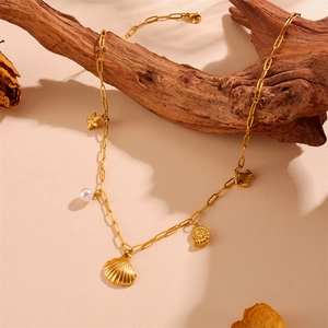 Détail d'un collier marin doré avec pendentifs coquillage, étoile de mer et perle