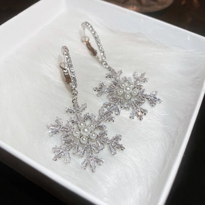 Macro shot of silver snowflake earrings with cubic zirconia and faux pearl accents