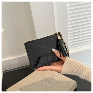 Detail of a black crocodile texture coin purse with gold chain and tassel accent