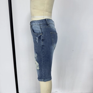 Détail d'un short en jean bleu avec déchirures latérales et finition délavée effilochée