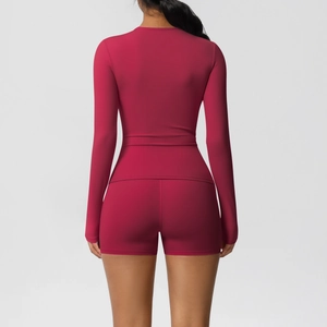 Detail of berry red seamless yoga set featuring tight long sleeve top and athletic shorts