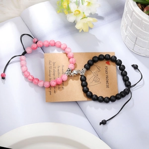 Detail of pink and black beaded couple bracelets with magnetic heart charm and adjustable cord