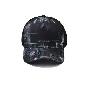 Detail of baseball cap showing black tie-dye pattern, green letters and mesh back
