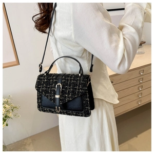 Detail of tweed crossbody bag with gold hardware worn by model in a minimalist room