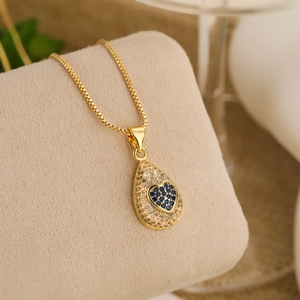 Detail of 18K gold teardrop pendant necklace featuring a blue heart-shaped zircon stone