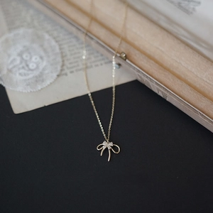 Close-up of golden S925 sterling silver double-layered bow necklace with crystals