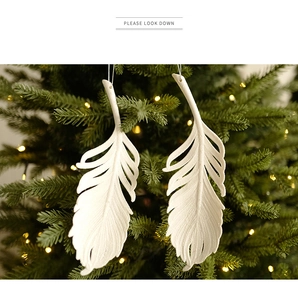 Close-up of white glittery feather ornaments hanging on a festive Christmas tree