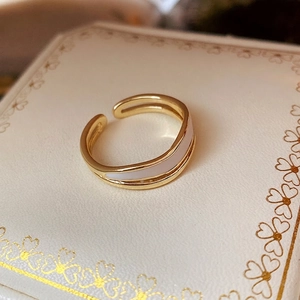 Elegant gold double-layered open ring with white enamel finish on a luxury jewelry box