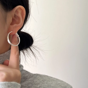 Close-up of a large minimalist brushed silver hoop earring worn on model profile