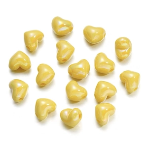 Macro shot of 16 yellow heart-shaped polished beads for DIY jewelry making and crafts