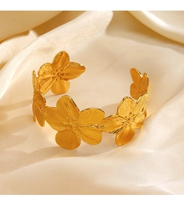 Dettaglio di un bracciale a fascia con fiori dorati e petali opachi su seta bianca