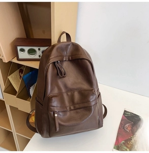 Detail of minimalist dark brown PU leather backpack on a desk with vintage props