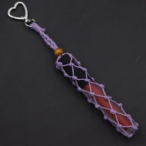 Detail of purple hand-woven lipstick holder keychain with heart-shaped silver metal clasp