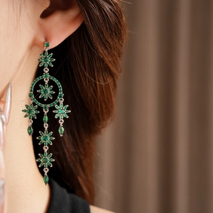 Detailed view of silver flower tassel earrings with green crystals on a model