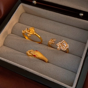 Detail of vintage gold snake, dragon, and rose rings set with white zircon in jewelry box