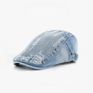Macro detail of distressed denim flat cap with vintage frayed holes and metal buckle