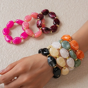 Detail of colorful resin beaded bracelets with irregular oval shapes and gold accents