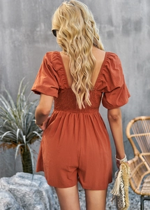 Detail of terracotta jumpsuit with puff sleeves and back cutout design in back view