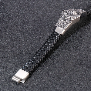 Detail of black braided leather bracelet with silver skull charms and magnetic clasp
