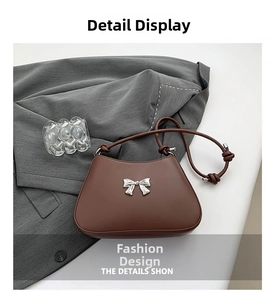 Detail of a dark brown shoulder bag featuring a silver metal bow and knotted strap