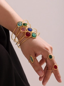Detailed view of colorful faceted glass gemstones on slim gold adjustable bracelets