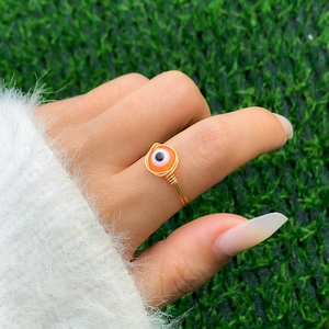 Macro detail of handmade gold wire-wrapped ring with orange evil eye bead embellishment