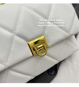 Detail of the golden rectangular twist lock on a white quilted leather flap handbag
