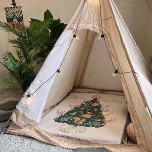 Detail of Christmas tree knit blanket with Merry Christmas text in a cozy camping setup