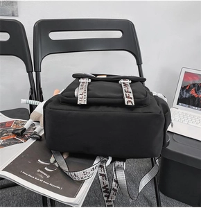 Close-up of black nylon backpack featuring industrial style printed straps and lettering