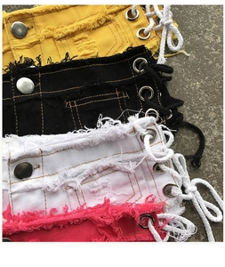 Dettaglio degli shorts in denim a vita bassa con lacci laterali e bordi sfrangiati