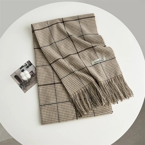 Detail of beige houndstooth scarf showing soft cashmere-like texture and fashion label
