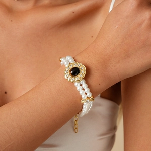 Detailed macro view of a double-layered pearl necklace with a gold floral pendant