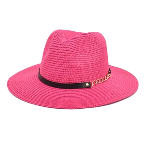 Detailed texture of rose red straw hat with black leather band and gold chain decoration