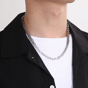 Detailed close-up of geometric silver stainless steel rectangular link chain on male model