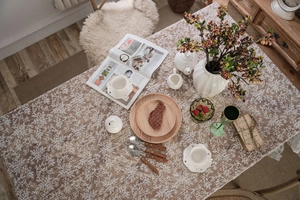 Detail of white embroidered tablecloth on a wooden table with elegant floral patterns