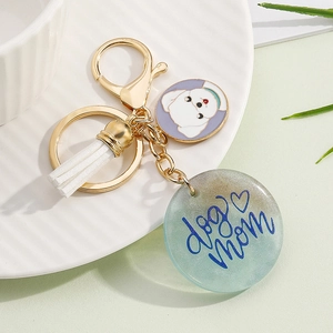 Detail of a resin dog mom keychain with a white tassel and enamel Bichon Frise charm