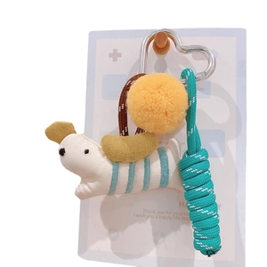 Plush fabric puppy keychain with yellow pompom and blue woven rope on a gift card