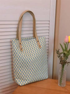 Détail du sac cabas floral aux motifs de losanges jaunes et bleus et anses en cuir brun