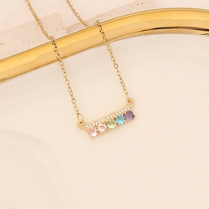 Detail of gold necklace with rectangular pendant featuring multi-colored gemstones