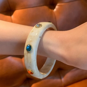 Detail view of a vintage marble resin bangle featuring colorful inlaid gemstones and metal claws