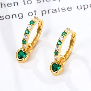 Detailed close-up of golden heart earrings with green zircon and sparkling stones