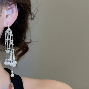 Detail of silver long tassel earrings with white pearls on a model showing elegant drape