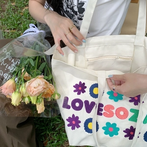 Close-up of flower embroidery texture and zippered inner pocket on canvas tote bag