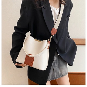 Detail of white PU leather bucket bag with brown patches and beige wide strap