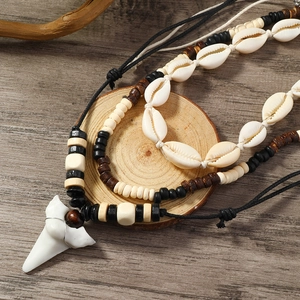 Detail of bohemian layered shell necklace with shark tooth pendant on a wooden background