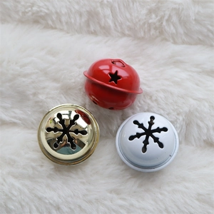 Three metal Christmas bells with star and snowflake patterns on white fur background