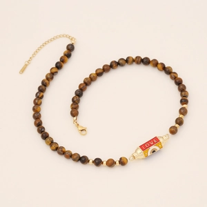 Detail of tiger eye bead necklace with LOVE enamel evil eye pendant and gold clasp